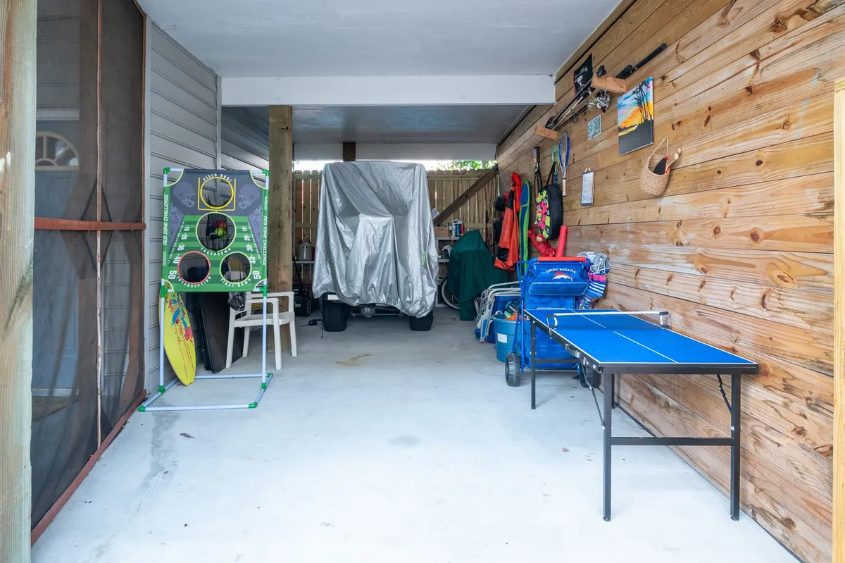 A relaxed, playful scene featuring a ping pong table and sporting equipment, set in a multi-use area that encourages family game nights and summer gatherings. The casual atmosphere suggests fun indoor activities for all ages.
