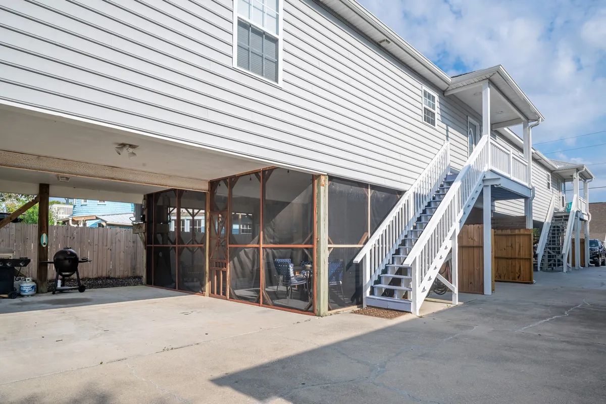 This image prominently features the screened patio area, complete with a grill, outdoor seating, and direct access via a staircase. The seating area is arranged for gatherings, and the grill suggests opportunities for outdoor cooking and family feasts.