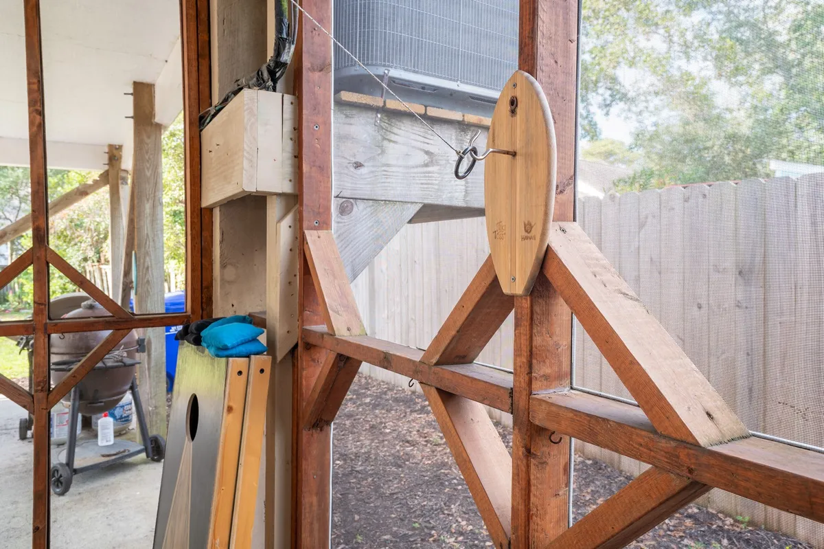 A view from inside looking out through large windows, featuring rustic wooden beams and a pulley. The outdoor setting is visible beyond the glass, emphasizing a seamless connection between the indoor lounge and nature—perfect for sunsets or hosting friends.
